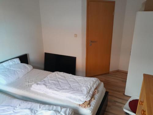 an unmade bed in a room with a door at Monteurswohnung Eisenberg in Eisenberg