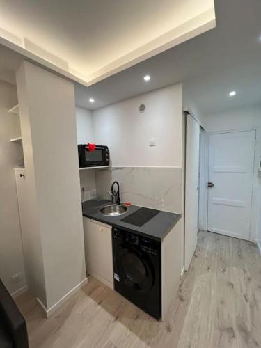 une petite cuisine avec un évier et un micro-ondes dans l'établissement Appartement de luxe PARIS 16, à Paris
