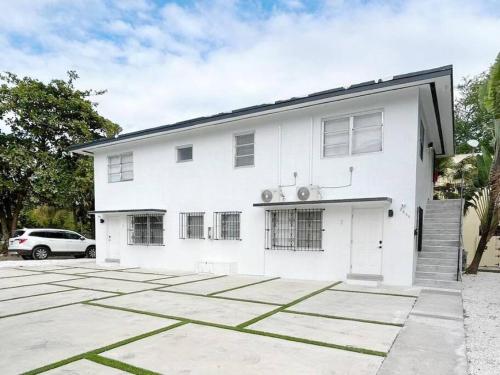 a white house with a car parked in front of it at Fully equipped Apartments with parking near Cocowalk in Miami
