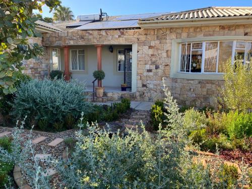 a stone house with a garden in front of it at Nama-Nama Guestrooms in Vredendal