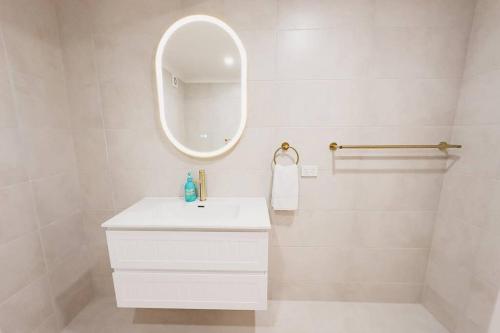 a white bathroom with a sink and a mirror at Beachside Villa #3 in Yeppoon