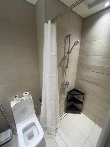a bathroom with a toilet and a shower with a shower curtain at The Perfect Couples Nest in Dubai