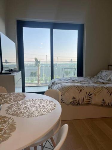 a bedroom with a bed and a table and a window at The Perfect Couples Nest in Dubai
