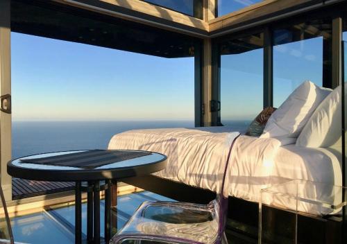 a bedroom with a bed and a table on a balcony at Atatū PurePod in Tormore