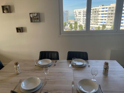 une table en bois avec des assiettes et des verres à vin dessus dans l'établissement L'Horizon, à Calais
