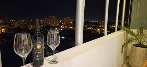 a bottle of wine and two wine glasses on a balcony at Delta Boutique Loft, en el centro de Salta, p/ 3 in Salta