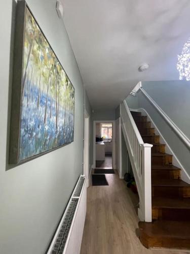 a hallway with a staircase with a painting on the wall at House 246 in Birmingham