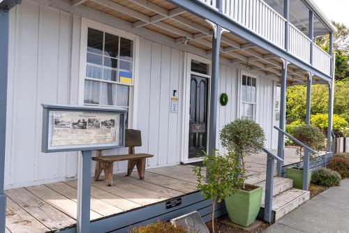 a porch of a house with a bench on it at The Old Oak Boutique Hotel in Mangonui
