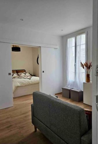 un salon avec un canapé et un lit dans l'établissement Cocon élégant à 10 min de Paris et de La Défense, à Houilles