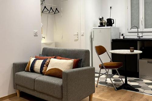 un salon avec un canapé et une table et une cuisine dans l'établissement Cocon élégant à 10 min de Paris et de La Défense, à Houilles