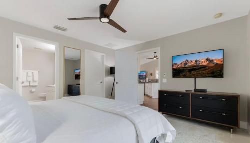 a white bedroom with a large bed and a flat screen tv at Tranquil Palms Heated Pool Spa Outdoor TV & More in Cape Coral