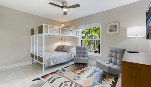a bedroom with a bed and a chair and a window at Tranquil Palms Heated Pool Spa Outdoor TV & More in Cape Coral