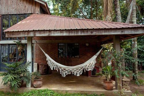 a small house with a hammock in front of it at The River Villa Situated In A Lush Garden in Arusha