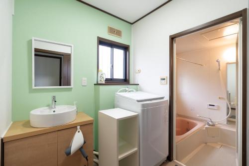 a bathroom with a sink and a toilet and a tub at Hamanoakariya Kujukuri in Katakai
