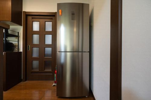 a stainless steel refrigerator in a kitchen with a door at Hamanoakariya Kujukuri in Katakai