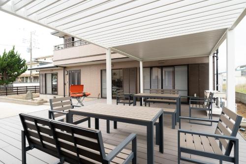a patio with a wooden table and chairs at Hamanoakariya Kujukuri in Katakai