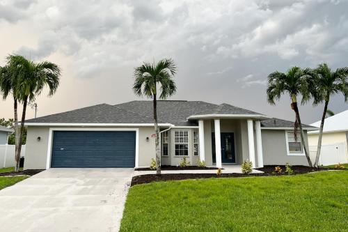 珊瑚角Pelican House 4 bedrooms Free Heated Pool的一座白色的房子，前面有棕榈树