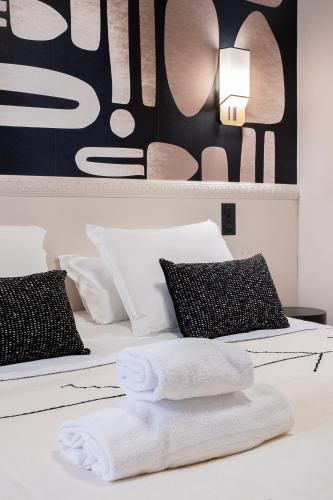 a white bed with two black and white pillows at Host Inn Bien-être SPA JACUZZI Downtown in Lyon