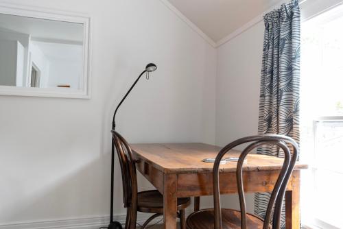 a dining room table with two chairs and a lamp at The Old Oak Boutique Hotel in Mangonui