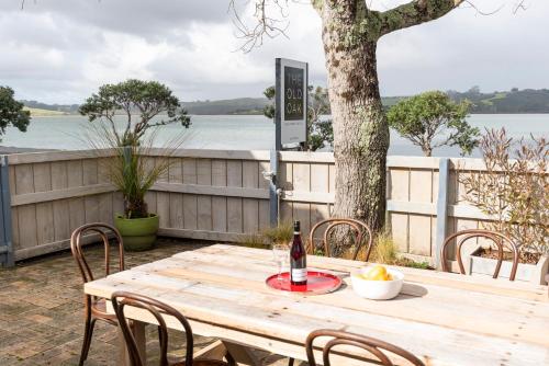 a wooden table with a bottle of wine and chairs at The Old Oak Boutique Hotel in Mangonui