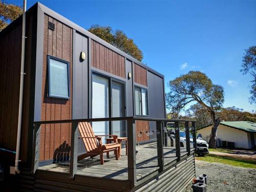 a house with a deck with a chair on it at Braemar Bay Holiday Park in Kyloe