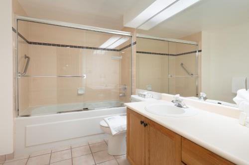a bathroom with a tub and a sink and a toilet at The Woodrun Lodge by Whiski Jack in Whistler