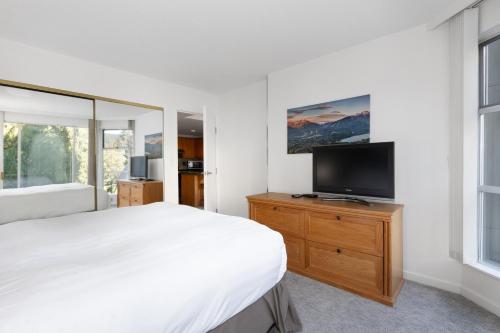 a bedroom with a bed and a tv on a dresser at The Woodrun Lodge by Whiski Jack in Whistler