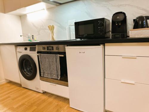 une cuisine avec un lave-linge et un micro-ondes dans l'établissement Appartement Cosy au Stade de France Proche Paris, à Saint-Denis
