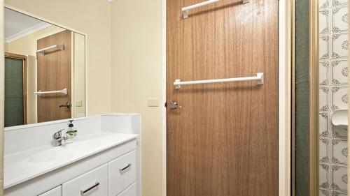 a bathroom with a sink and a wooden door at Myee Court in Urunga