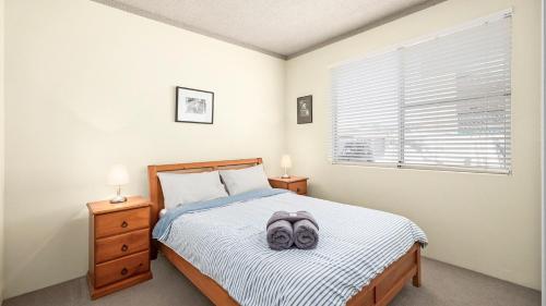 a bedroom with a bed with a pair of slippers on it at Myee Court in Urunga