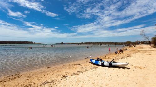 a boat on a beach with people in the water at Myee Court in Urunga