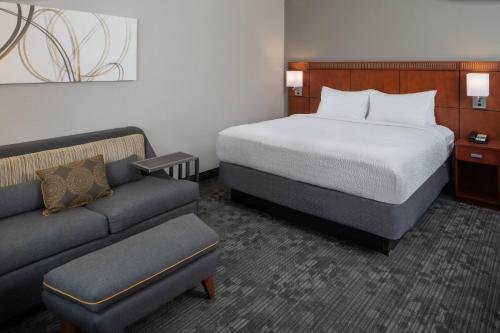 a hotel room with a bed and a couch at Courtyard by Marriott Nashville Airport in Nashville