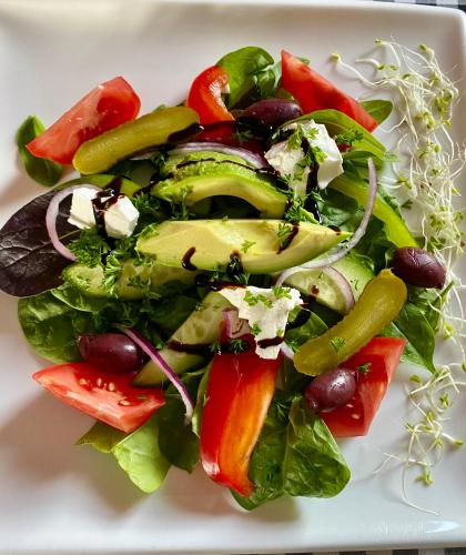a salad with vegetables on a white plate at The Cliffs Seaside Lodge in Tuatapere