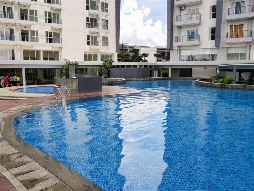 a large blue swimming pool in front of a building at Comfy and Cool Interior 1BR at Casa De Parco Apartment BSD By Travelio in Tangerang