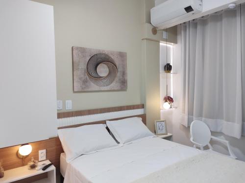 a bedroom with a white bed and a chair at Kitnet com vista do Pão de Açúcar e Enseada de Botafogo in Rio de Janeiro