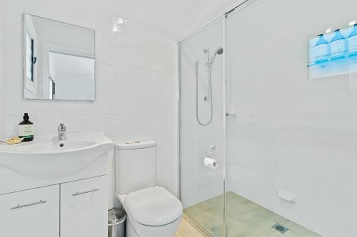a white bathroom with a toilet and a shower at Jado on the Lake - Captains Quarters in St Georges Basin