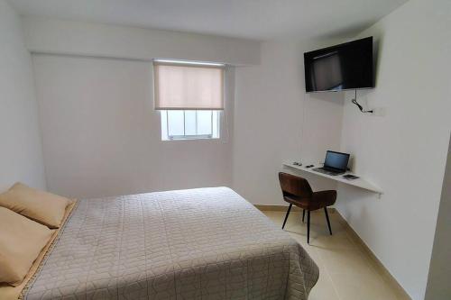 ルリンにあるDepartamento en playa Aricaのベッドと机とテレビのある寝室