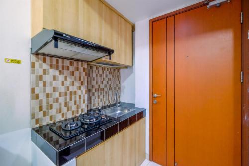 a small kitchen with a stove and a sink at Homey Studio at 10th Floor Margonda Residence 5 Apartment By Travelio in Depok