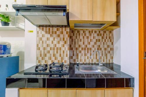 a kitchen with a stove and a sink at Homey Studio at 10th Floor Margonda Residence 5 Apartment By Travelio in Depok