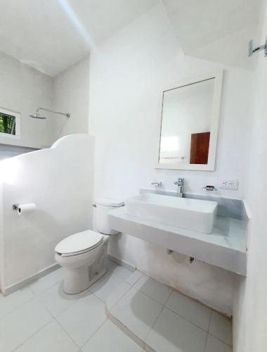 a white bathroom with a sink and a toilet at Casa Azul Cielo in Dzilam de Bravo