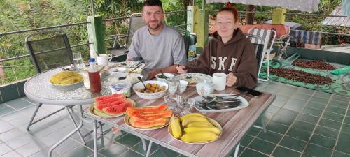 two people sitting at a table with food on it at Rohana Estate Lodging & Camping in Kandy