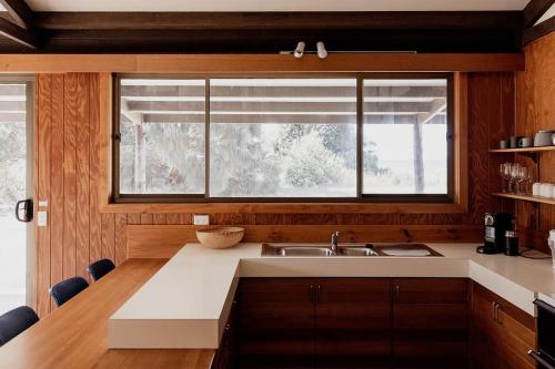 eine Küche mit Spüle und Fenster in der Unterkunft Waterfront Boltons Beach Cottages in Little Swanport