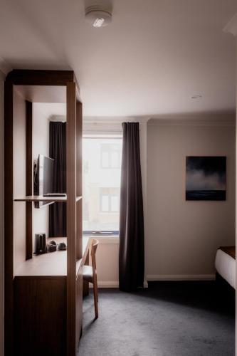 a bedroom with a window and a table and a mirror at Shipwrights Arms Hotel in Hobart