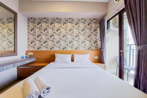 a bedroom with a large white bed and a window at Fancy and Nice Studio at Atria Residence Gading Serpong Apartment By Travelio in Tangerang