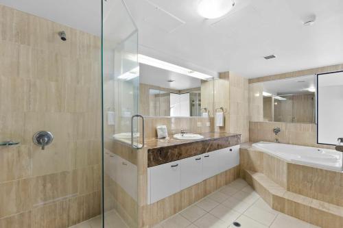 a bathroom with a tub and a sink and a shower at Neptune Resort in Gold Coast
