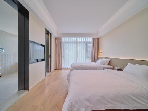 a hotel room with two beds and a flat screen tv at Jingdezhen Seven Bamboo Wind Over Ear Hotel in Xianghu