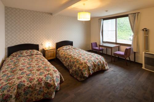 Una habitación de hotel con dos camas, un escritorio y una ventana. en SHIRETOKO Kokun Kekun, en Shari