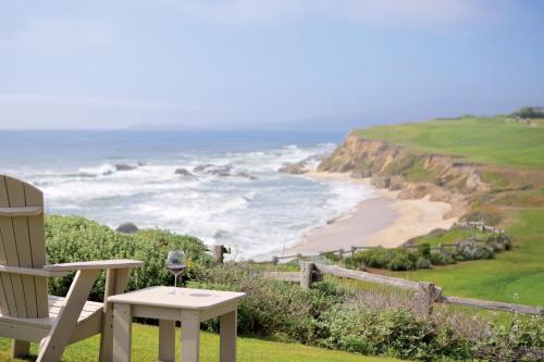 a chair and a glass of wine sitting next to a beach at The Ritz-Carlton, Half Moon Bay in Half Moon Bay