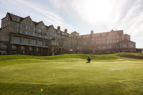 a man playing golf on a green in front of a large building at The Ritz-Carlton, Half Moon Bay in Half Moon Bay