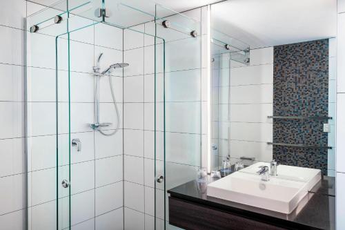 a bathroom with a sink and a glass shower at Four Points by Sheraton Auckland in Auckland